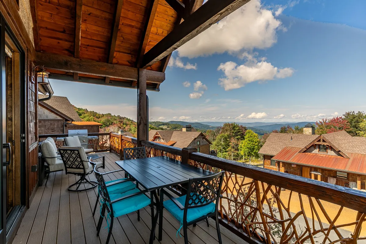 An outdoor dining area set under wooden beams, overlooking mountain vistas. The table is elegantly set up for meals, and comfortable seating invites guests to linger and enjoy the fresh air during sunrise coffee or evening gatherings.