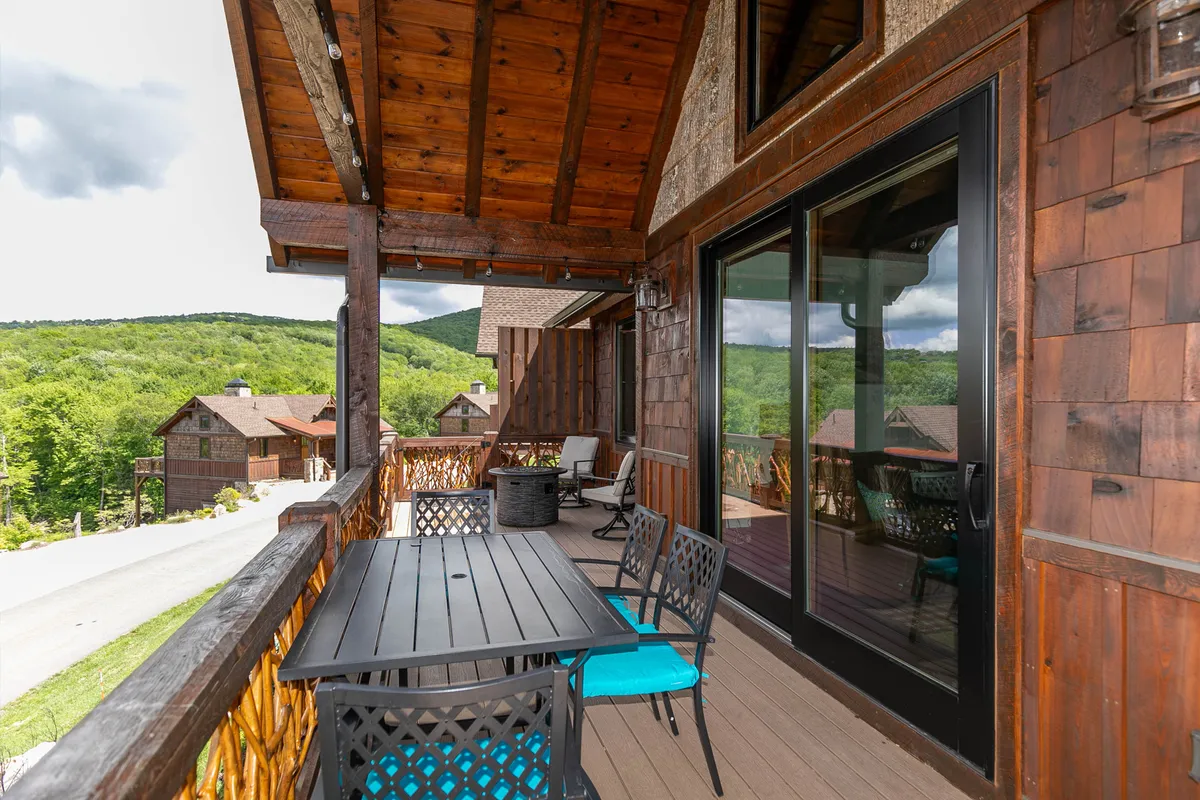 This image shows a spacious wooden deck furnished with outdoor seating and overlooking a beautiful mountain view. The tranquil setting is perfect for relaxing, enjoying the fresh air, and letting pets lounge safely in a contained space.